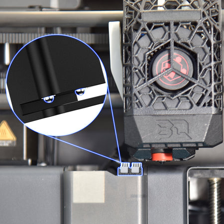 Close-up of a 3D printer with a focus on a component and a magnified detail.