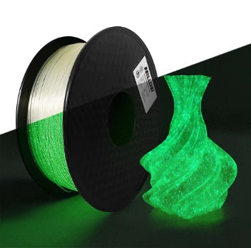 Spool of green glow-in-the-dark filament next to a glowing green vase on a black background