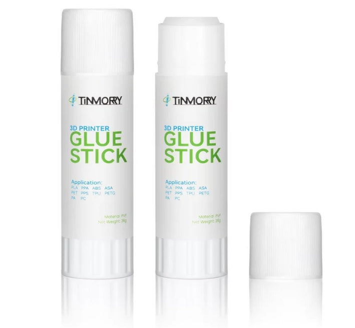 Two white Timmory 3D Printer Glue Sticks with green and blue text, shown on a white background with one cap placed beside them.