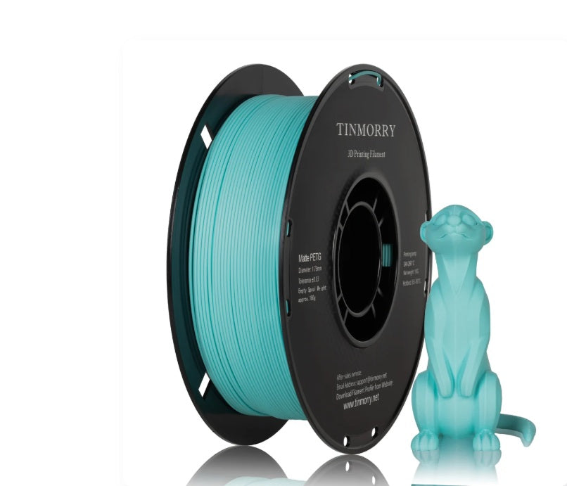 A spool of turquoise 3D printing filament next to a small turquoise 3D-printed cat figurine on a clean white background. The spool features the brand name TINMORRY printed on its black outer rim.